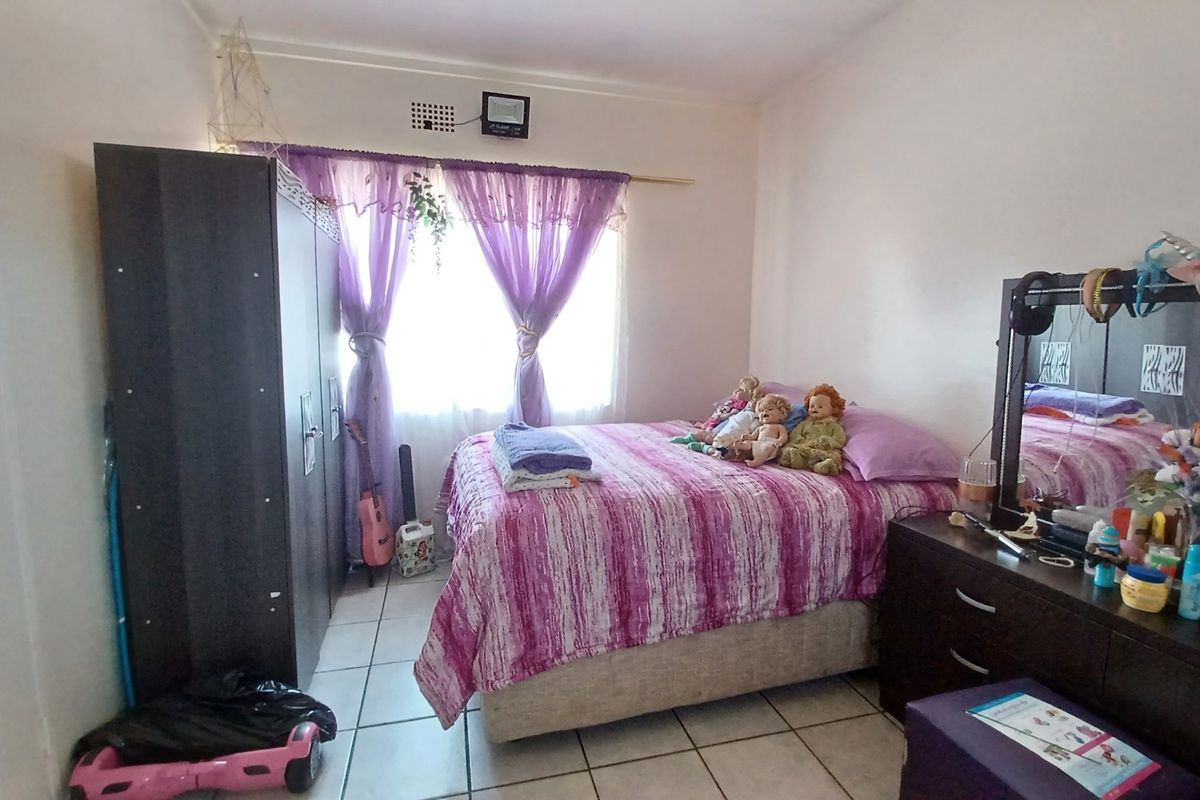 A bedroom featuring tiled flooring and a window with curtain rod, offering a functional space for rest.