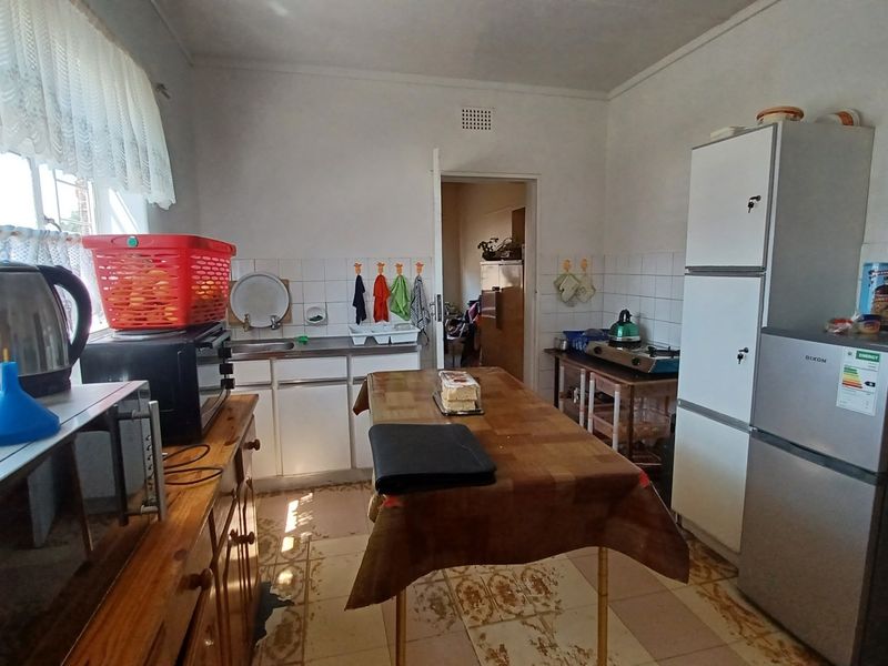 A functional kitchen featuring tiled flooring, a tiled splashback, and built-in cabinetry, offering a dated aesthetic with potential for modernization.