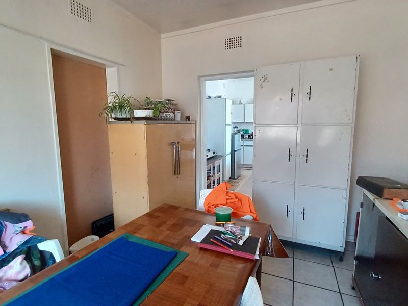 Dining area featuring tiled flooring and built-in storage cupboards, with an open transition leading through to the kitchen area.