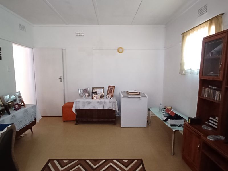 A simple living room featuring neutral walls, vinyl flooring, and ceiling ventilation, offering a blank canvas for potential interior updates.