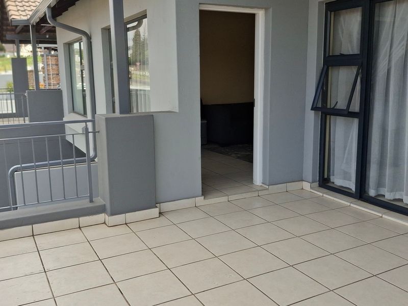 A spacious tiled balcony featuring a metal balustrade and aluminium sliding door access to the interior living area.