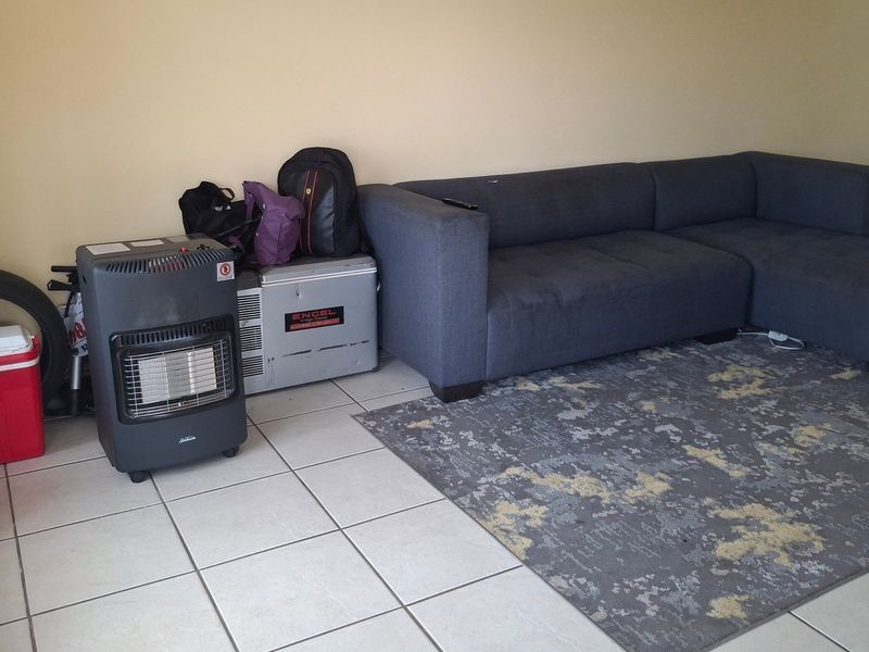 A living room area featuring neutral wall tones and tiled flooring, providing a functional space for relaxation.