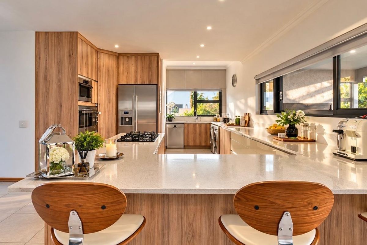 Modern kitchen featuring wood-finish cabinetry, stone countertops, a central island with a gas hob, and high-end integrated appliances.