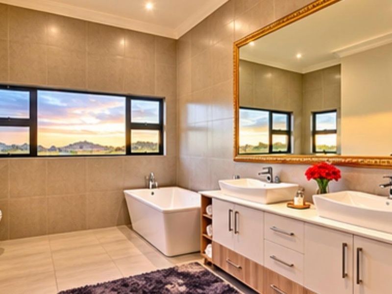 Modern bathroom featuring a freestanding bathtub, double vanity with vessel sinks, large framed mirror, and expansive windows with scenic views.