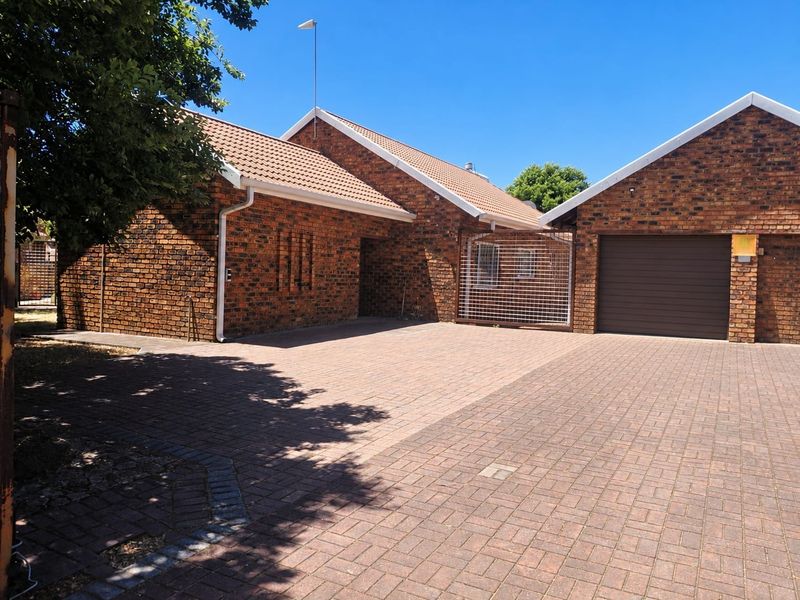 Front exterior view of a face brick house featuring a paved driveway, tiled roof, and an integrated garage.