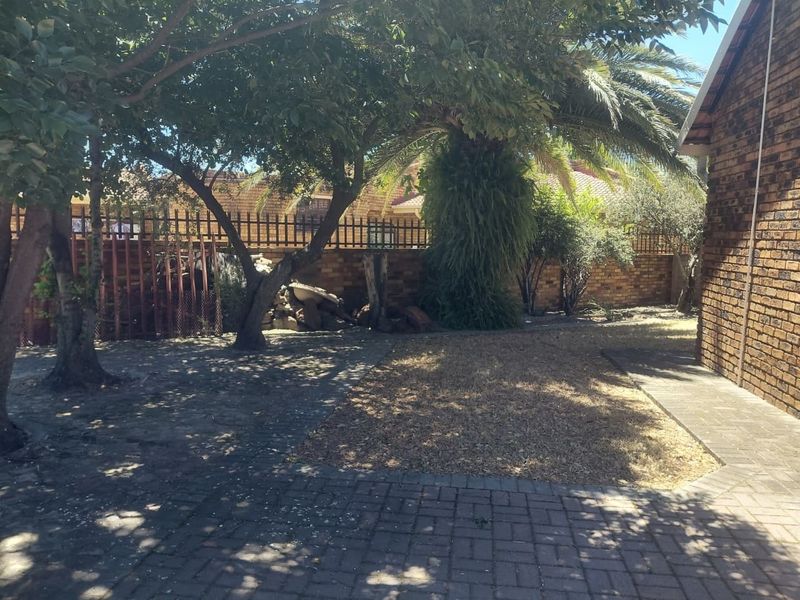 A rear garden area featuring brick boundary walls, paved sections, and established trees, providing a private outdoor space.