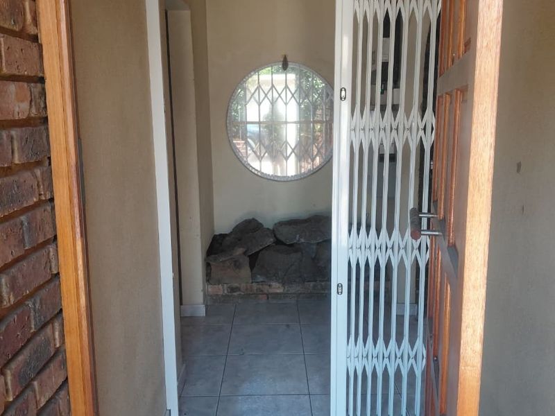 Entrance area featuring tiled flooring, a security gate, and a circular window, providing a functional transition space into the home.