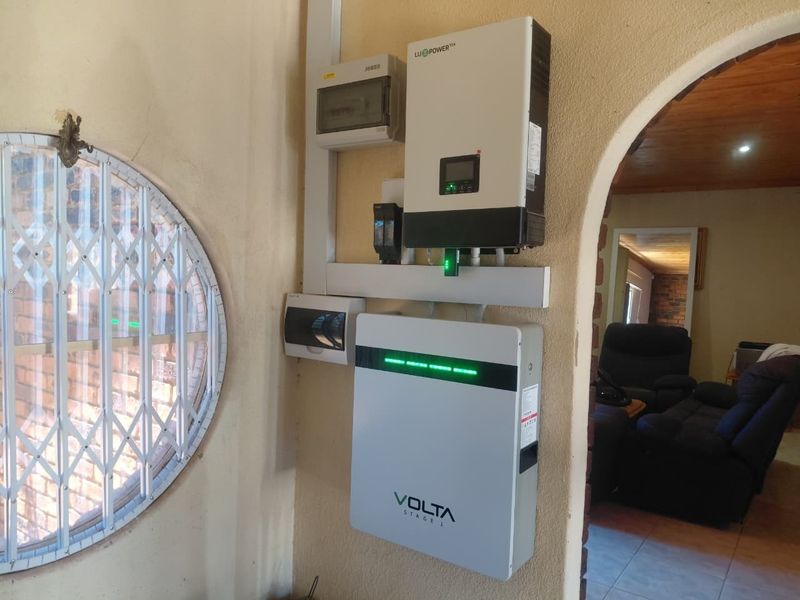 Utility area featuring a wall-mounted solar inverter and lithium battery storage system for residential power backup.