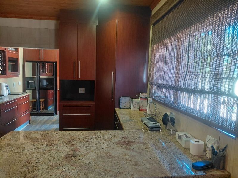 A functional kitchen featuring rich timber cabinetry, granite countertops, and a warm timber ceiling, offering a classic and durable workspace.