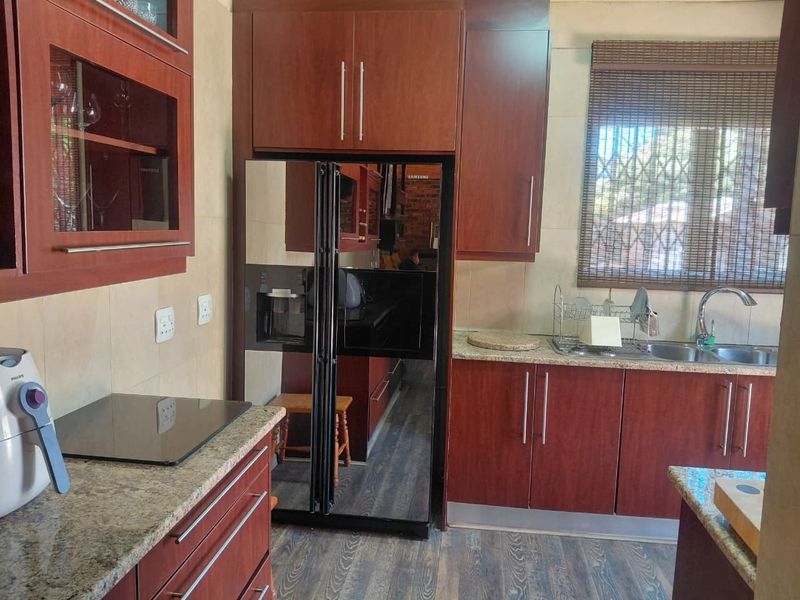 A functional kitchen featuring cherry wood cabinetry, granite countertops, and a stainless steel double sink with a window security gate.