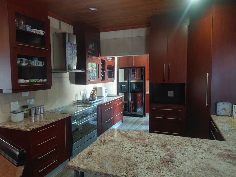A well-appointed kitchen featuring dark wood cabinetry, granite countertops, a stainless steel oven, and a warm timber ceiling.