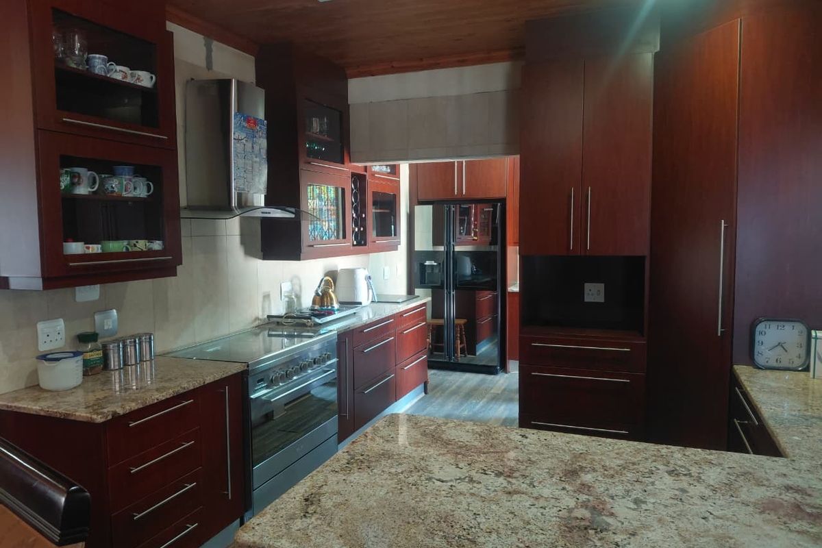 A well-appointed kitchen featuring dark wood cabinetry, granite countertops, a stainless steel oven, and a warm timber ceiling.