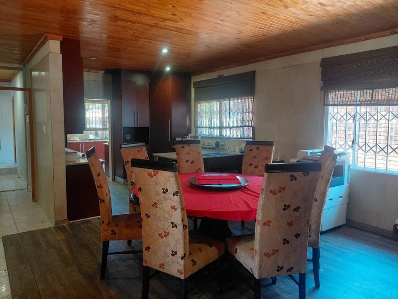 Open-plan dining and kitchen area featuring timber ceilings, laminate flooring, and built-in cabinetry with integrated kitchen workspace.