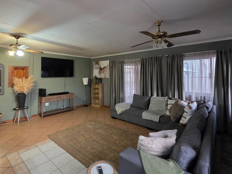 Spacious living room featuring tiled flooring, dual ceiling fans, and direct access to the exterior via sliding doors.