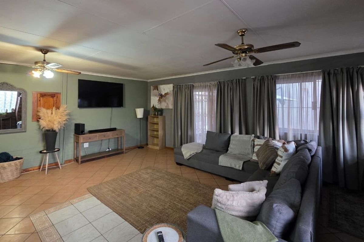 Spacious living room featuring tiled flooring, dual ceiling fans, and direct access to the exterior via sliding doors.