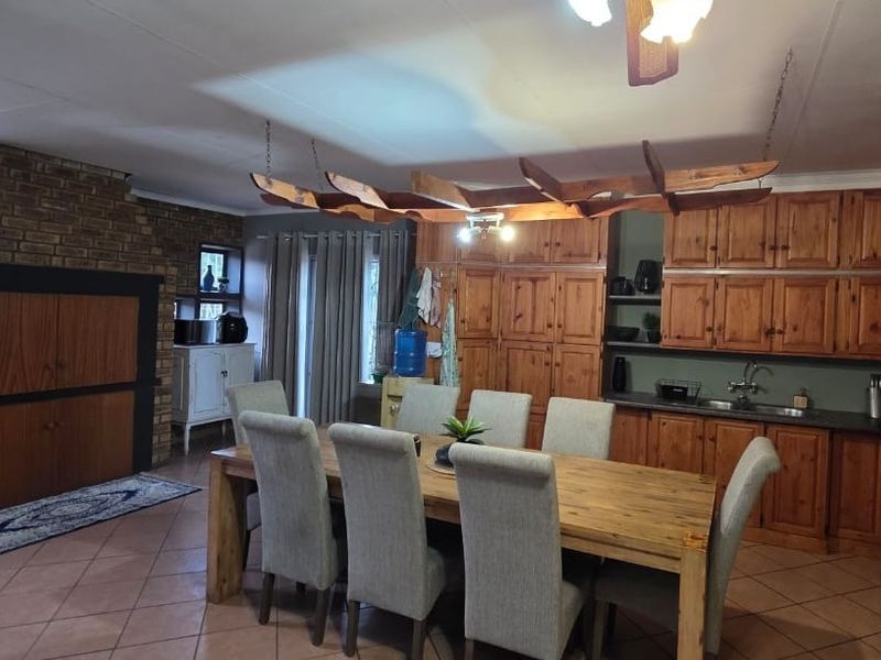Spacious open-plan kitchen and dining area featuring extensive wooden cabinetry, a brick fireplace, and tiled flooring, offering a warm and functional living space.