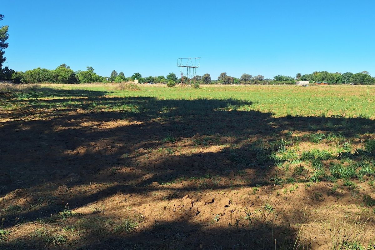 A wide, open plot of land featuring a metal water tower structure and natural vegetation, suitable for agricultural or development purposes.