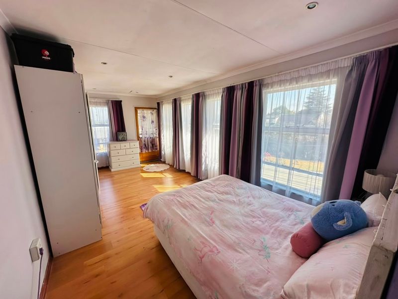 A spacious bedroom featuring hardwood flooring, recessed lighting, and large windows that provide ample natural light.