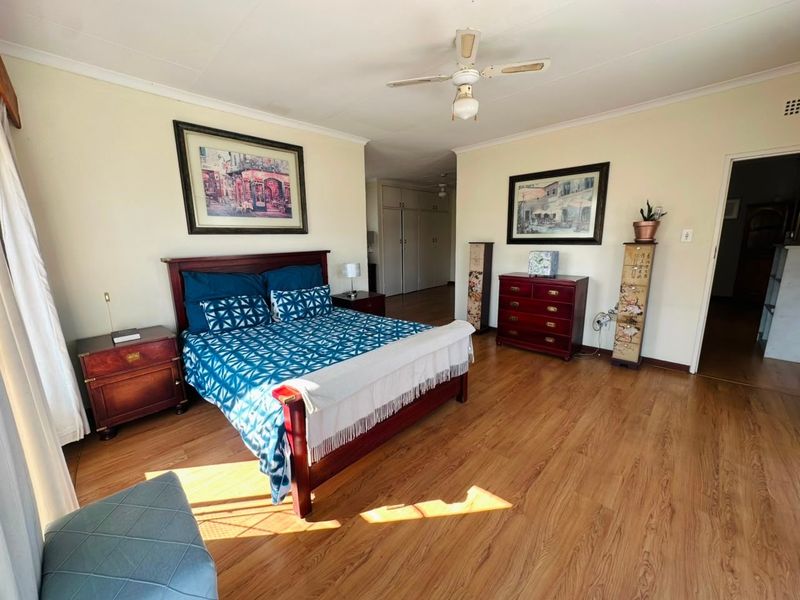 Spacious bedroom featuring laminate flooring, a ceiling fan, and built-in storage cupboards.