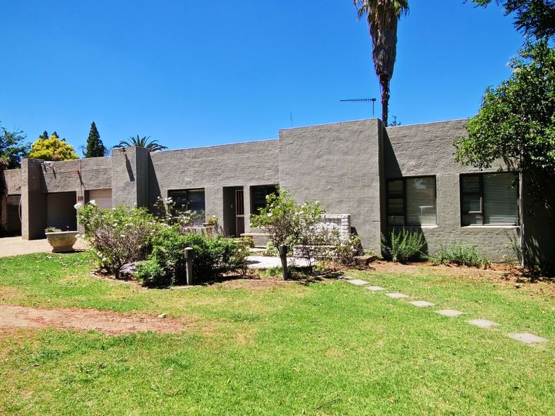 Front elevation of a single-story house featuring a stucco facade, attached garage, and a landscaped front garden with a stone pathway.