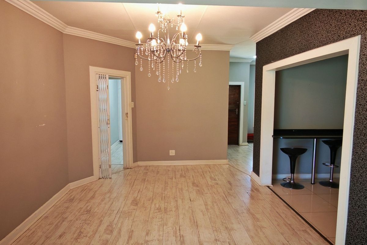 Spacious living area featuring light wood-look laminate flooring, decorative crown molding, and a convenient built-in breakfast bar nook.