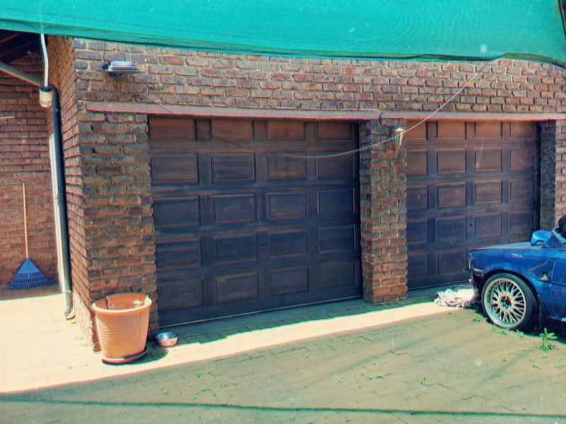 A double garage with face brick exterior and paved driveway, featuring a shade cloth awning for additional protection.