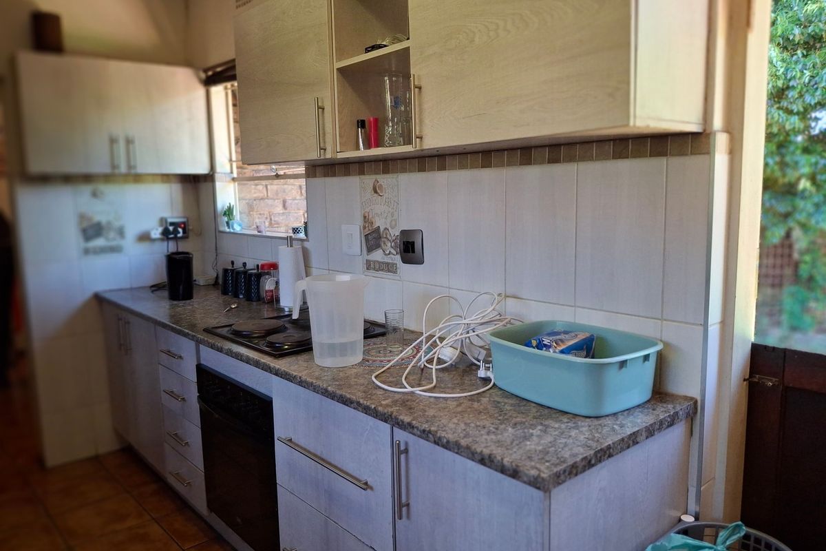 A functional kitchen featuring laminate cabinetry, tiled backsplash, built-in oven, and electric hob, with direct access to the outdoor area.