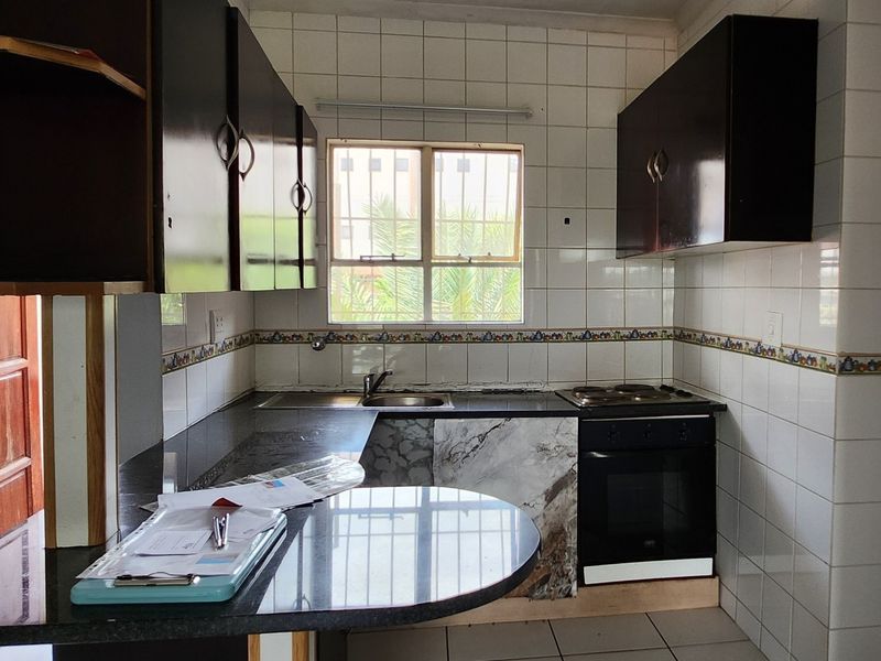 A functional kitchen featuring dark cabinetry, granite countertops, a built-in oven, and a tiled backsplash, offering a solid foundation for a modern renovation.