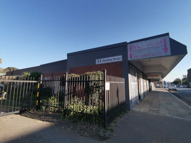 Front exterior view of a commercial office building on Harding Street, featuring a brick facade, metal security fencing, and a covered pedestrian walkway.