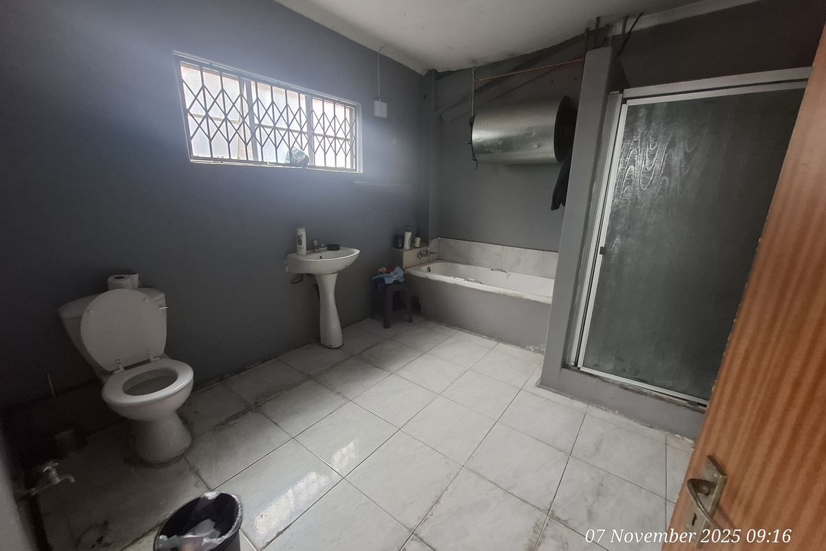 A functional bathroom featuring a pedestal basin, toilet, built-in bathtub, and a separate shower enclosure with tiled flooring.