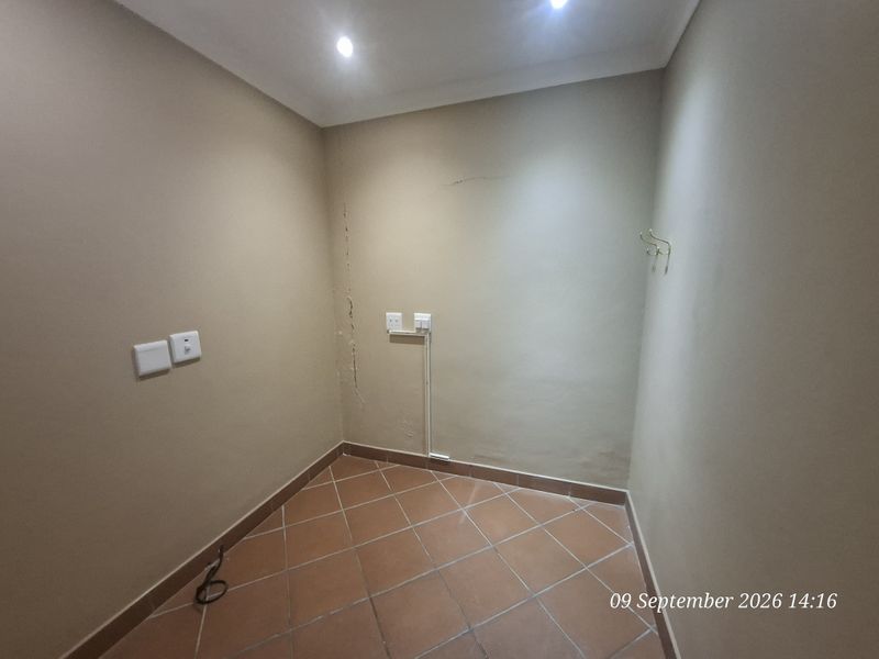 A small, empty office space featuring ceramic tiled flooring, recessed ceiling lighting, and visible wall cracks requiring maintenance.