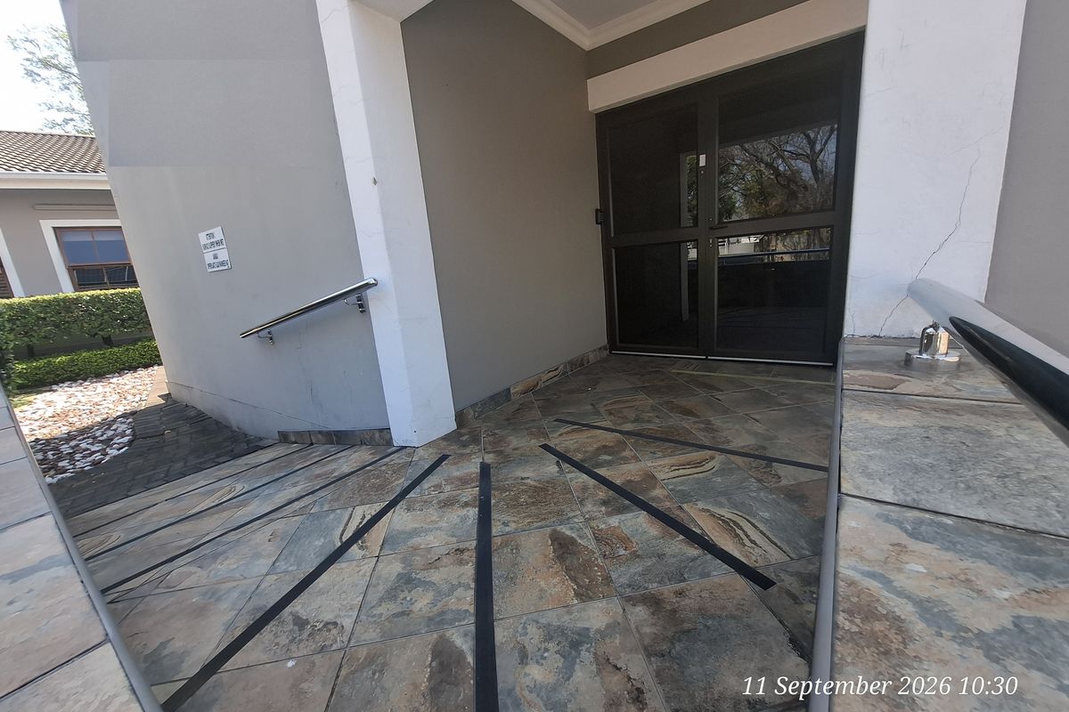 Accessible office entrance featuring a tiled ramp with stainless steel handrails and a glass door entry.