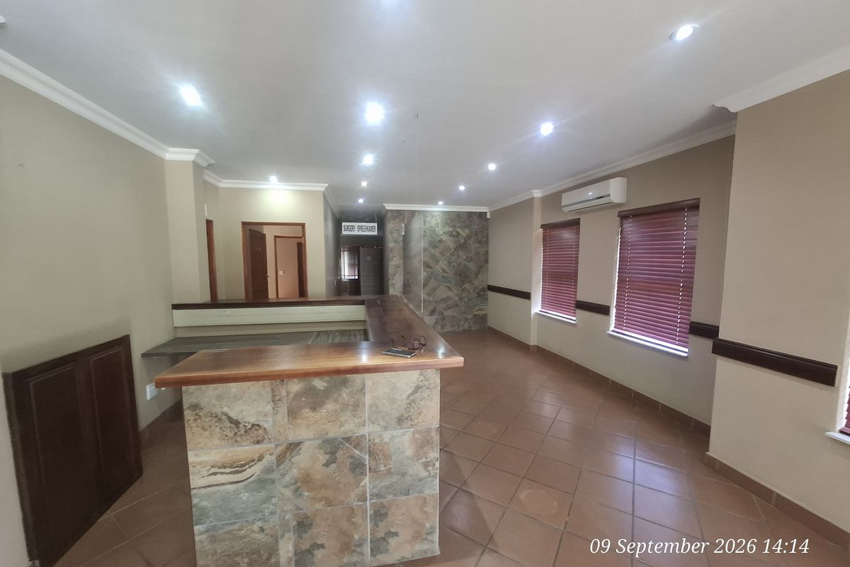 Spacious office area featuring a built-in reception desk with stone cladding, ceramic tiled flooring, recessed lighting, and air conditioning.
