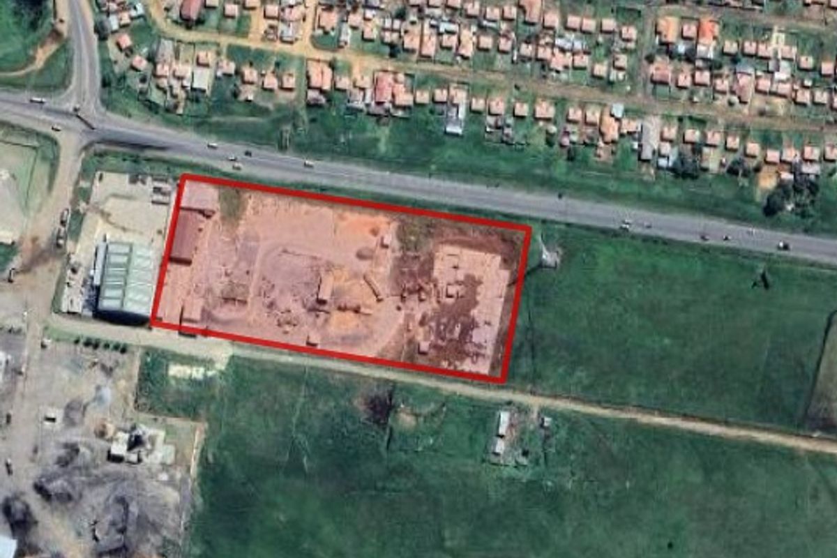 Aerial view of an industrial property site with clear boundary markings, situated near a main road and residential area.