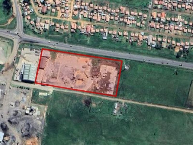 Aerial view of an industrial property site with clear boundary markings, situated near a main road and residential area.