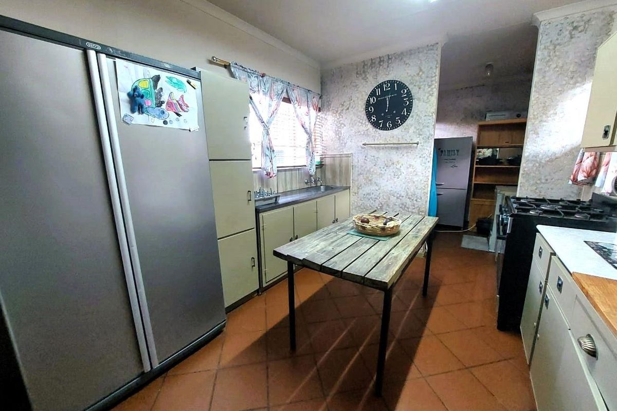 A dated kitchen featuring terracotta floor tiles, built-in cabinetry, and a gas stove, offering a functional layout with potential for modernization.