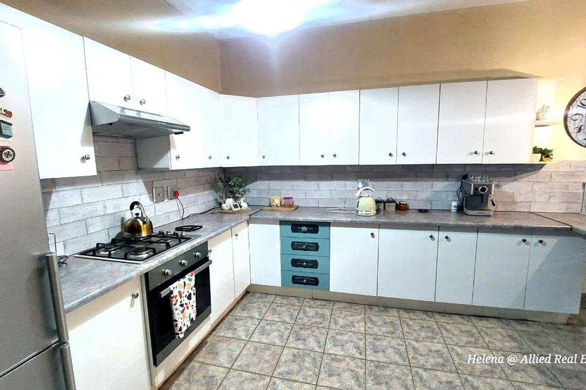A functional kitchen featuring white cabinetry, a built-in oven, gas hob, extractor fan, and a tiled backsplash with ample counter space.