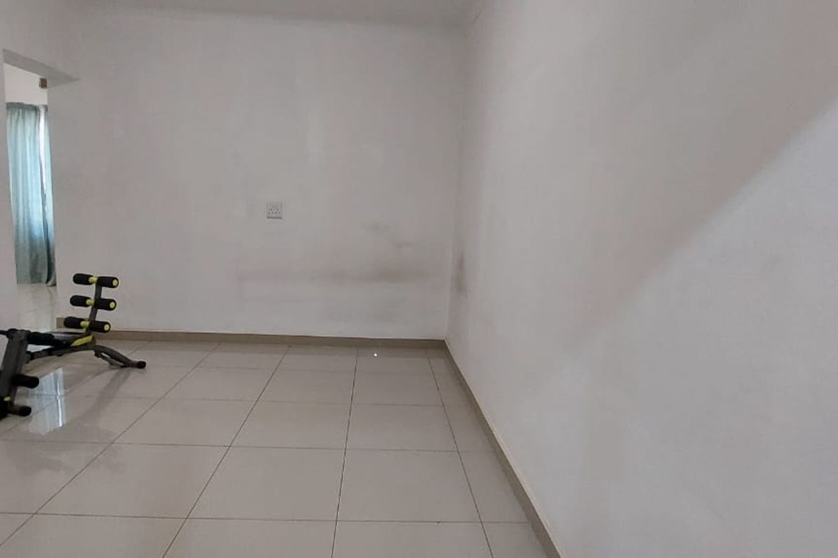 An empty living area featuring neutral floor tiles and plain white walls, offering a blank canvas for interior design.