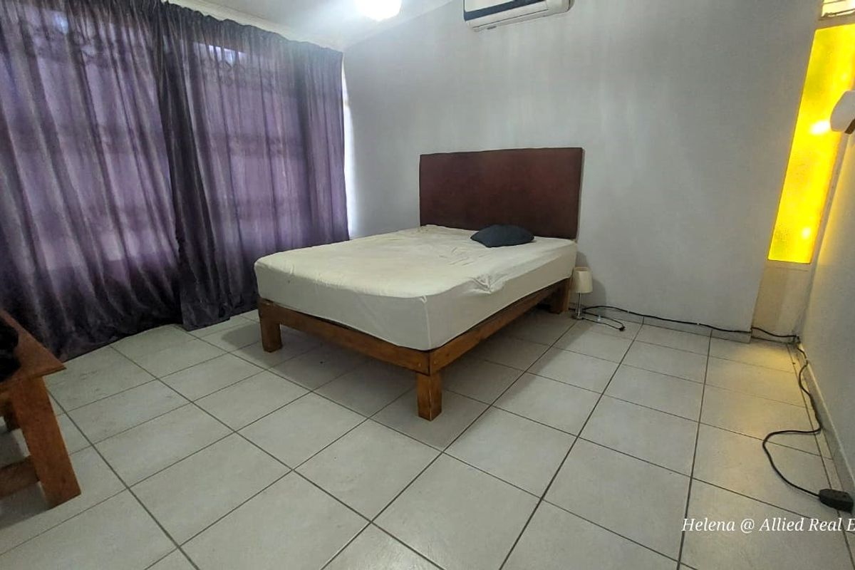 A bedroom featuring tiled flooring, a wall-mounted air conditioning unit, and large window curtains.