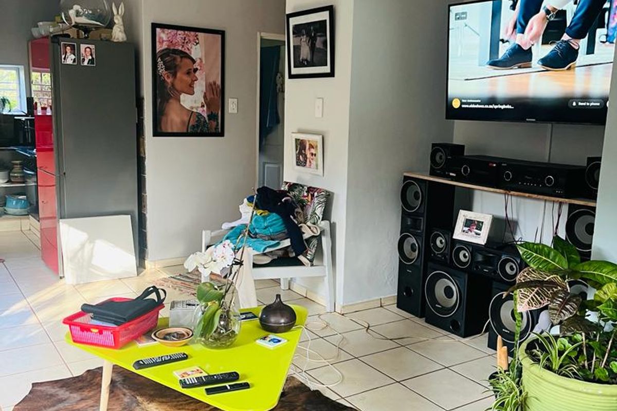 A living room area featuring tiled flooring, neutral wall tones, and a dedicated media wall setup.