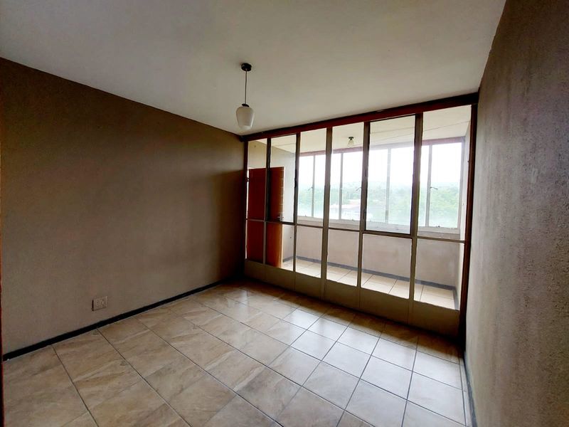 An enclosed balcony featuring tiled flooring and large windows, offering a versatile space that could be used as a sunroom or study area.