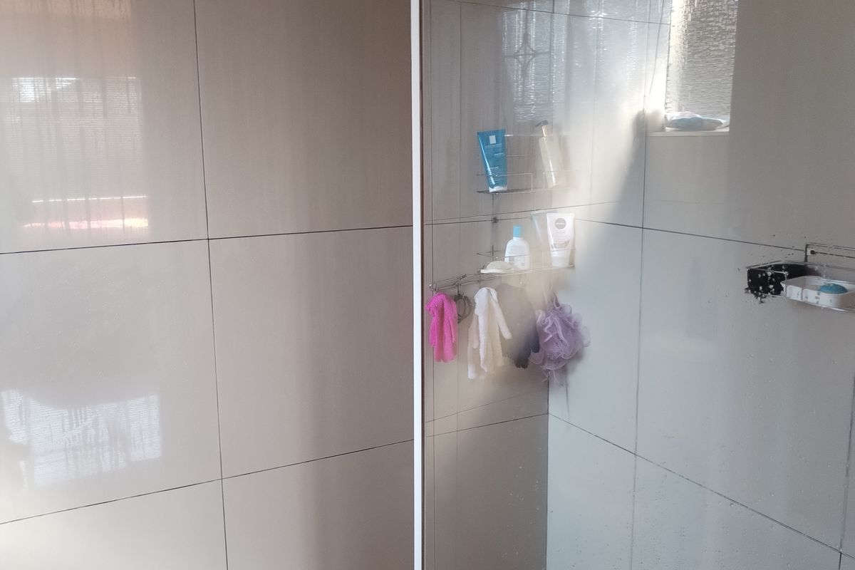 A modern walk-in shower featuring large format wall tiles, a glass enclosure, and a tiled floor with a built-in drain.