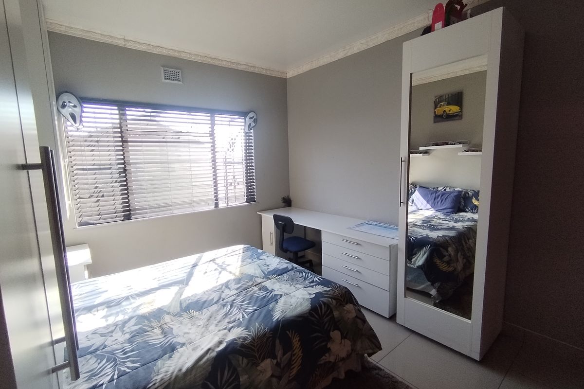 A functional bedroom featuring tiled flooring, built-in cabinetry, and a window with fitted blinds.