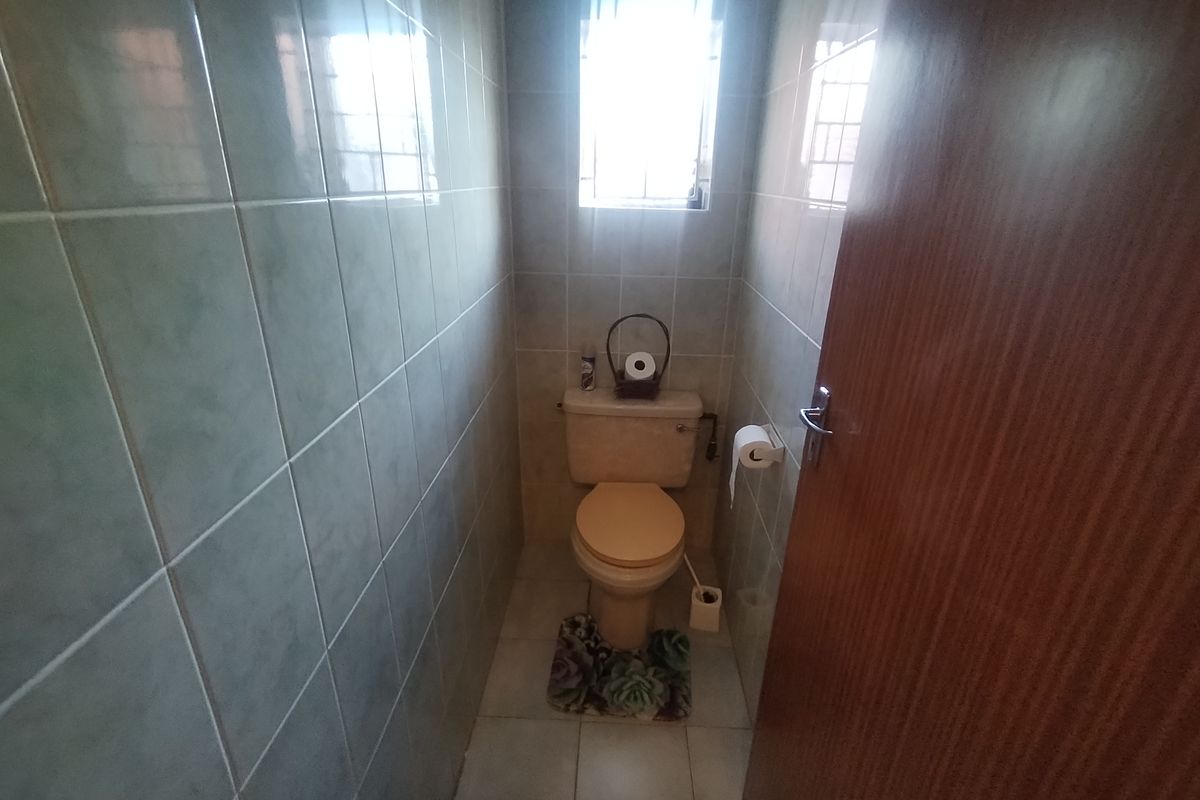 A compact, fully tiled guest toilet featuring a standard porcelain toilet suite and a small window for natural light.