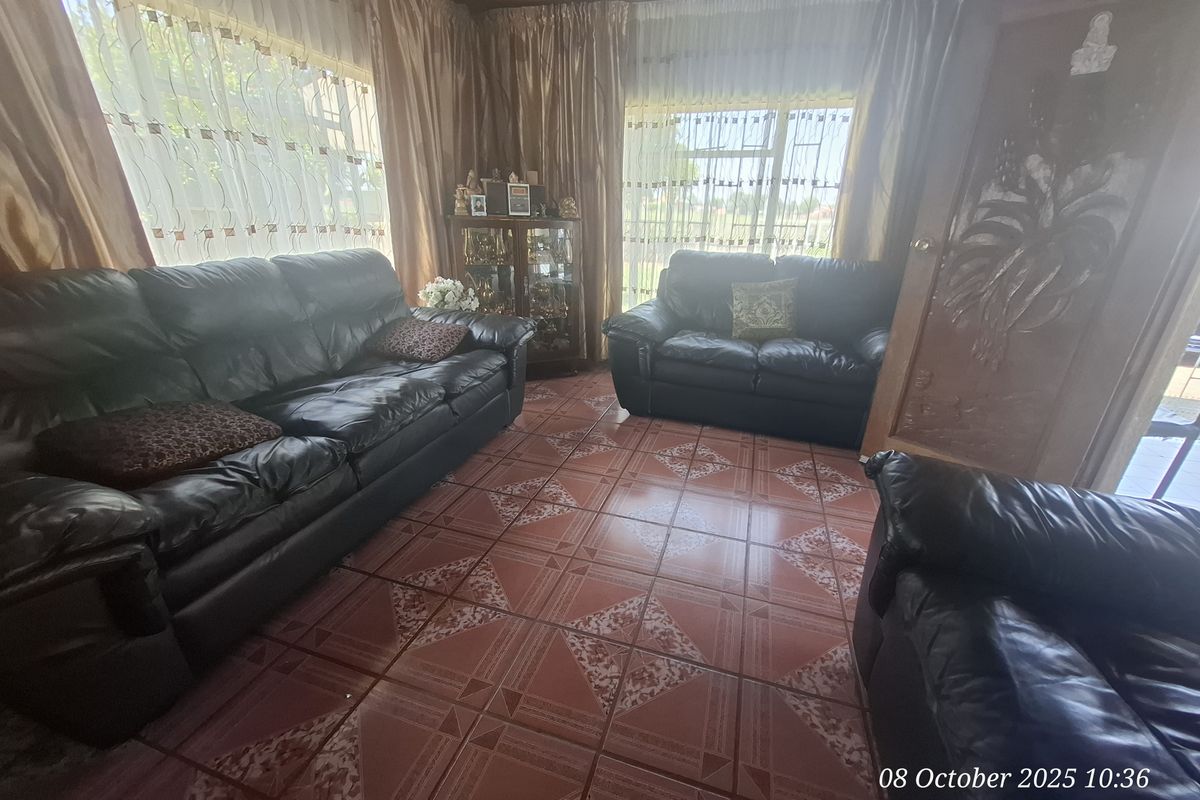 A living room featuring patterned ceramic floor tiles and a timber-paneled ceiling, providing a traditional aesthetic with large windows for natural light.