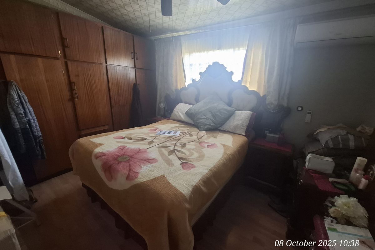 A bedroom featuring built-in wooden wardrobes, a ceiling fan, and a wall-mounted air conditioning unit.