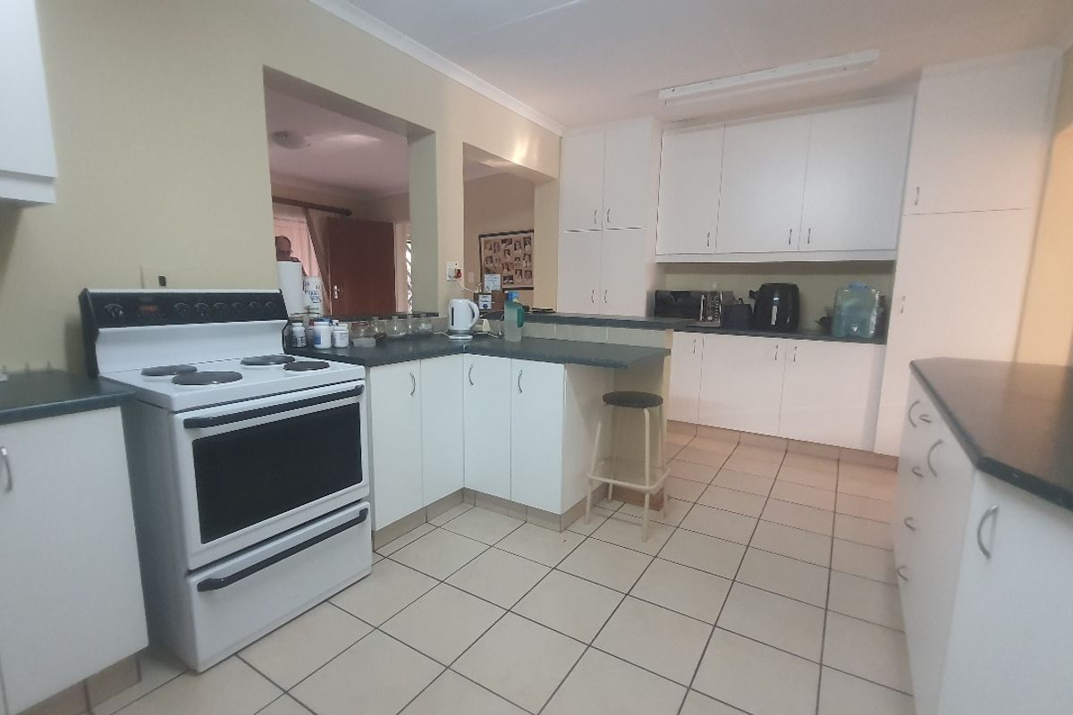 Functional kitchen featuring white cabinetry, dark countertops, tiled flooring, and a freestanding electric stove, offering a practical layout for daily meal preparation.