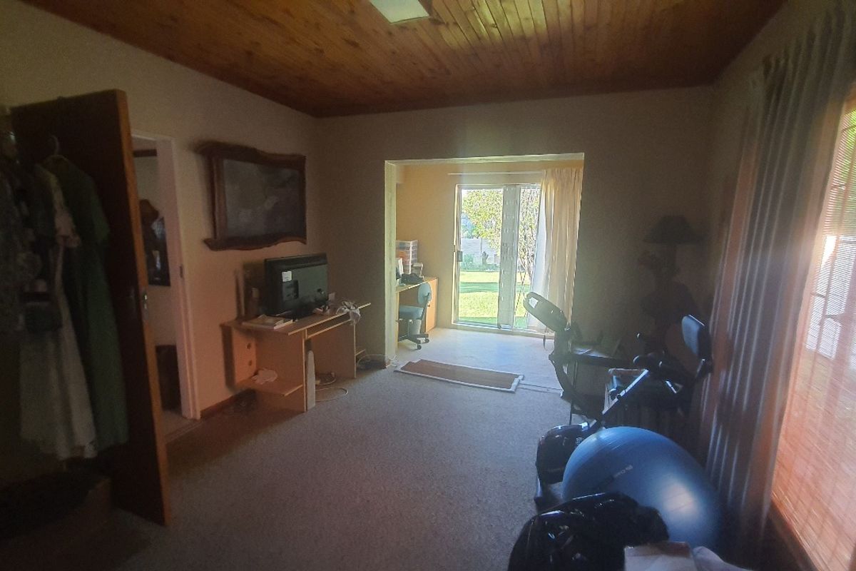 A living area featuring a timber-paneled ceiling, carpeted flooring, and sliding glass doors providing direct access to the rear garden.