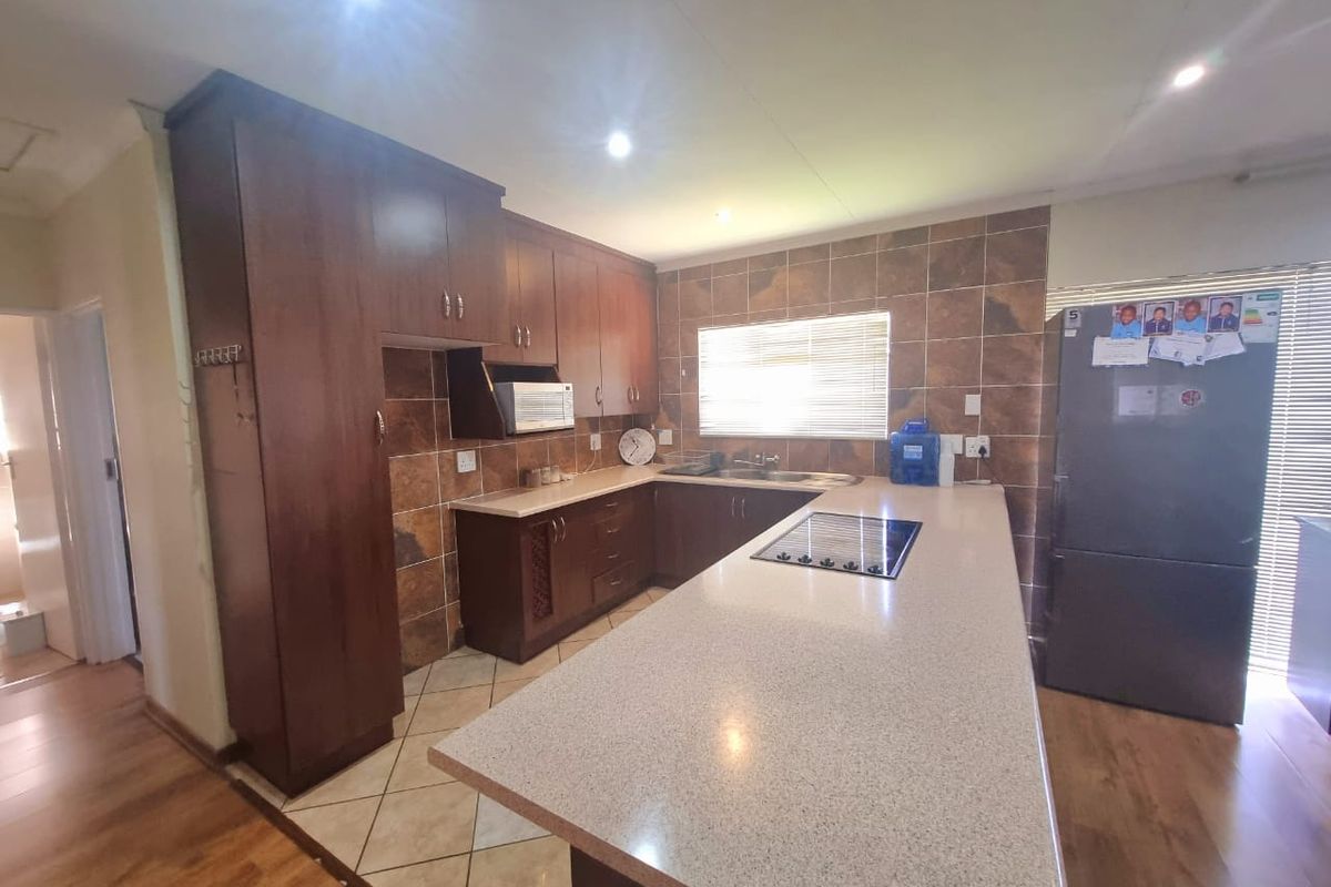 A functional kitchen featuring dark wood cabinetry, stone countertops, a built-in hob, and tiled backsplash with recessed lighting.