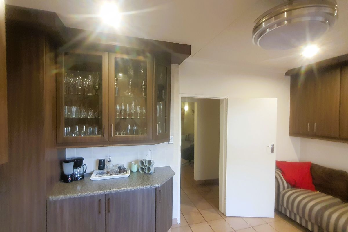 A kitchen area featuring dark wood cabinetry, stone-look countertops, and tiled flooring, with an open doorway leading to an adjacent room.